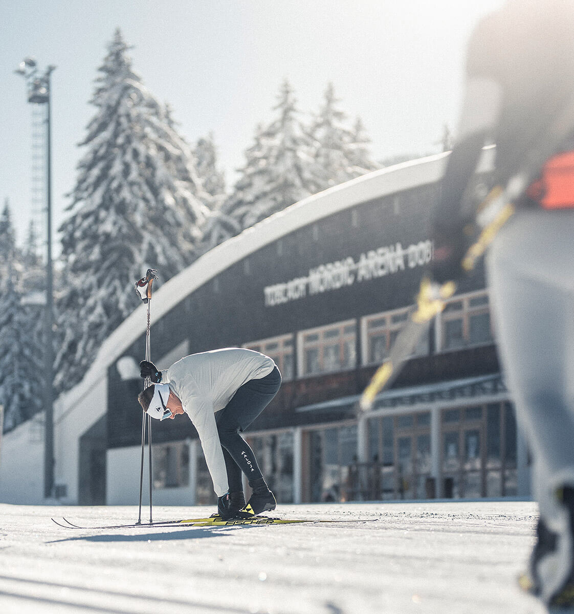 Ein Mann zieht seine Langlaufskier auf der Loipe an - Klaudehof