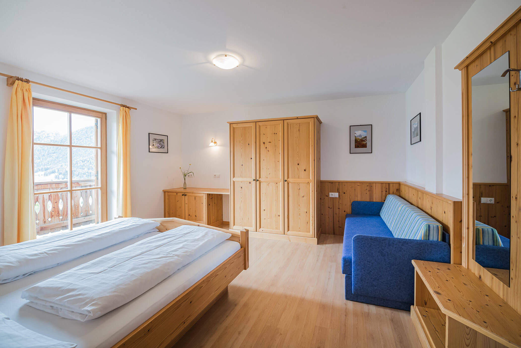 Schlafzimmer mit Doppelbett, Holzschrank und blauem Sofa - Klaudehof