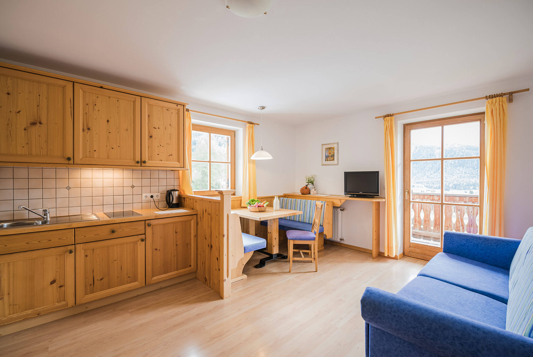 Wohnküche mit Ecktisch und blauem Sofa - Klaudehof