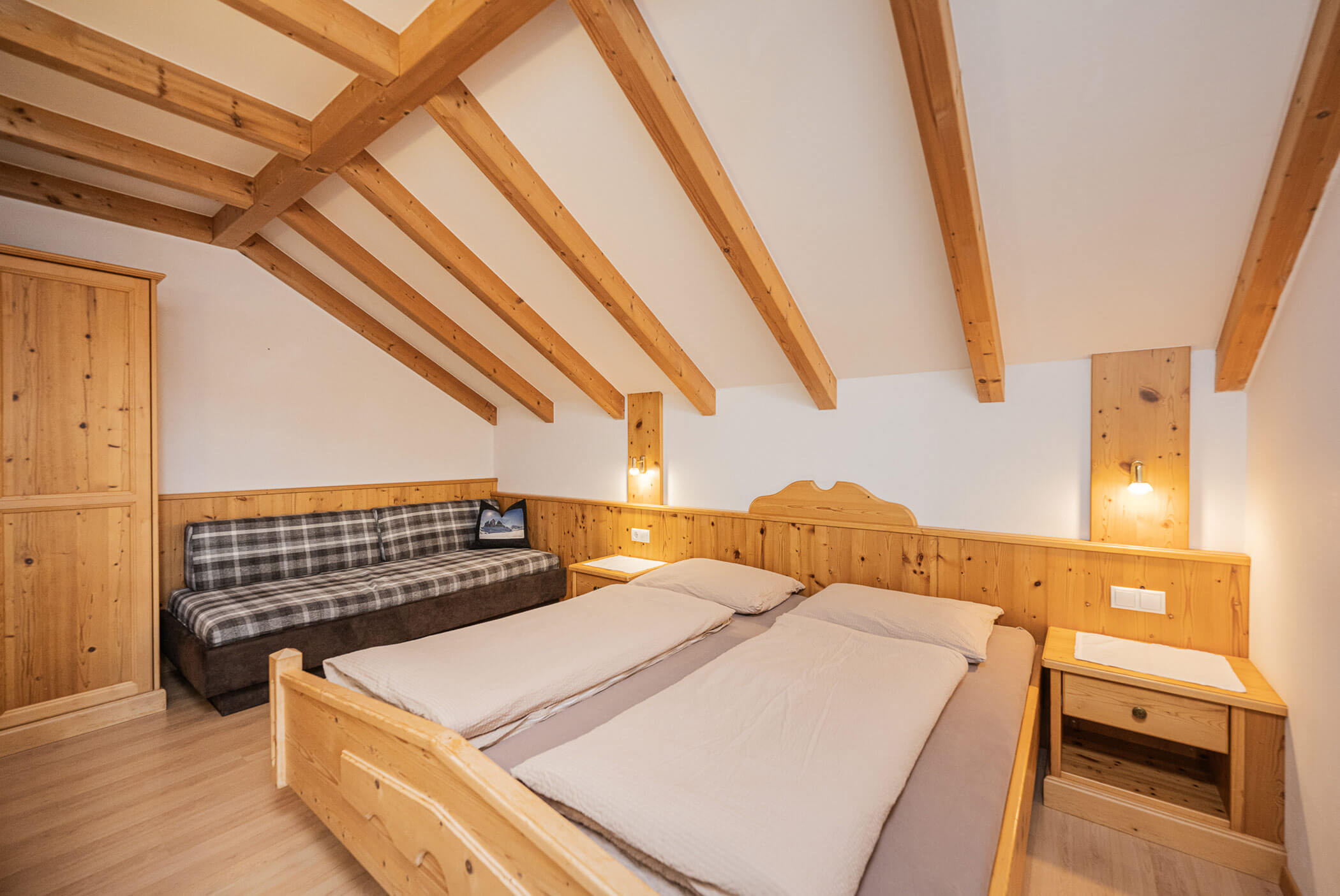 Doppelbett mit kariertem Sofa daneben - Klaudehof